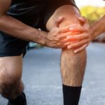 Athlete holding an unstable knee during sports activity after a ligament injury.