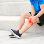 Person experiencing knee pain while climbing stairs and struggling with daily movement activities.