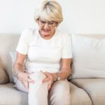 Middle-aged office worker experiencing knee stiffness after sitting for long hours at a desk.