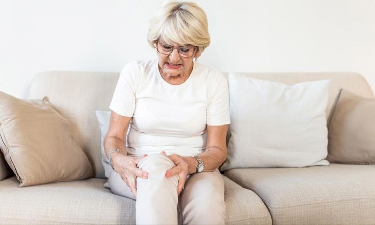 Middle-aged office worker experiencing knee stiffness after sitting for long hours at a desk.