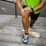 Man experiencing knee pain while walking upstairs due to early joint damage