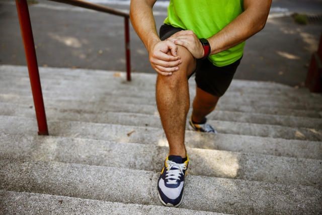 Man experiencing knee pain while walking upstairs due to early joint damage